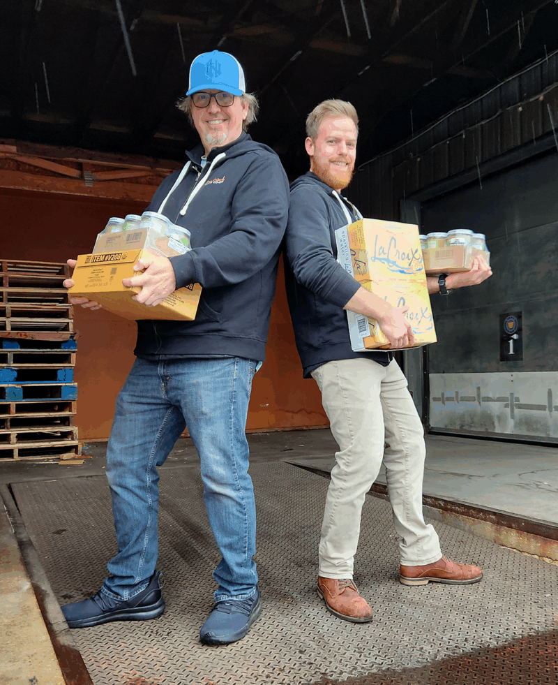 Two staff members standing on Monadnock Food Co-op's loading dock with cases of products.